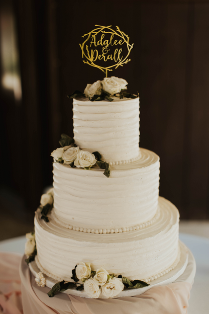 calligraphy personalized golden twig wreath style cake topper made of wood on top of the white simple wedding cake. 